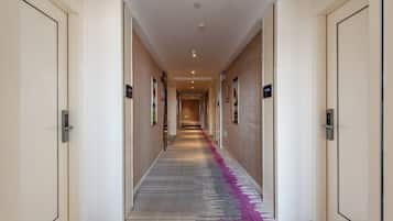 A hotel hallway with doors on both sides, a patterned carpet, and a ceiling light.