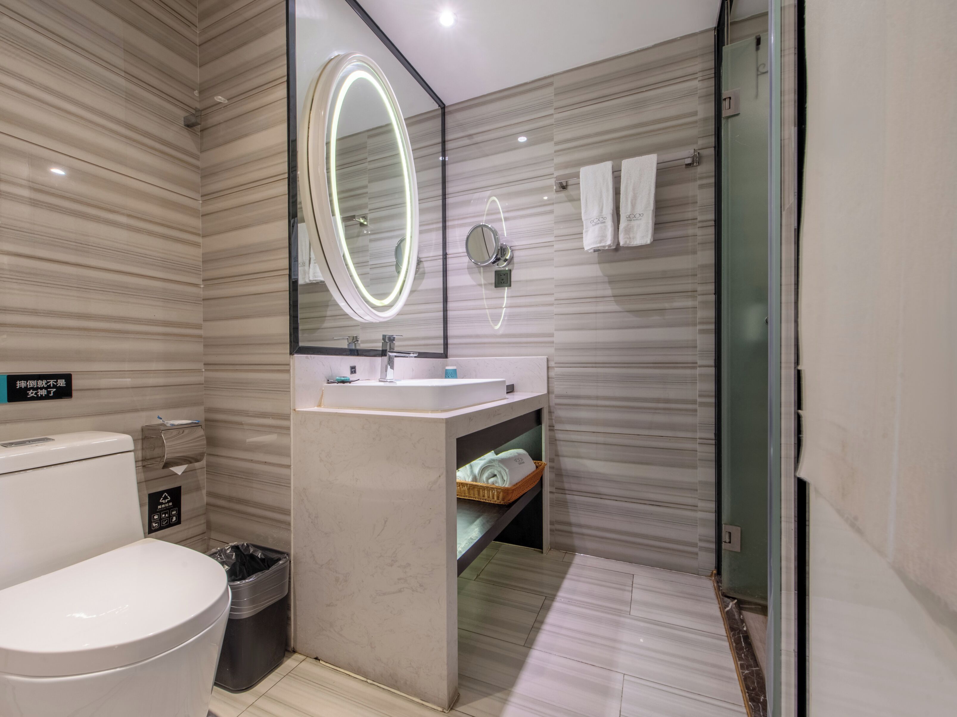 A modern bathroom with a toilet, bidet, vanity with a mirror, and a shower area.