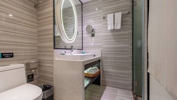 A modern bathroom with a toilet, bidet, vanity with a mirror, and a shower area.