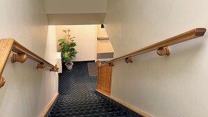 A staircase with a dark patterned carpet and wooden handrails. - Fairview Inn (Simcoe)