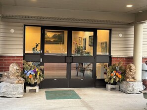 A hotel entrance with a black door, two lion statues, and a green mat. - Fairview Inn (Simcoe)
