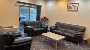 A room with two leather sofas, a small wooden coffee table, and a patterned carpet. - Fairview Inn (Simcoe)