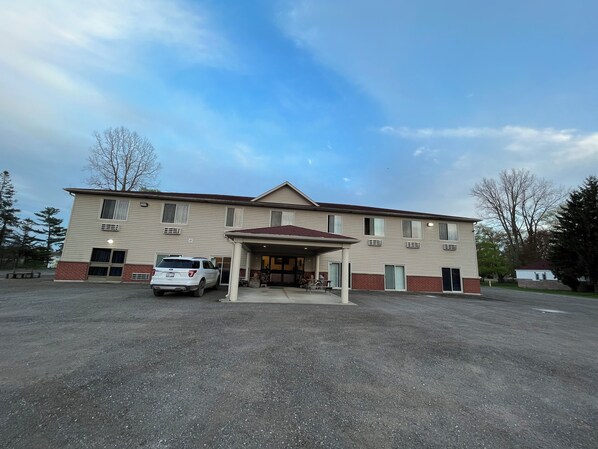 A two-story building with a covered entrance and a parking area. - Fairview Inn (Simcoe)
