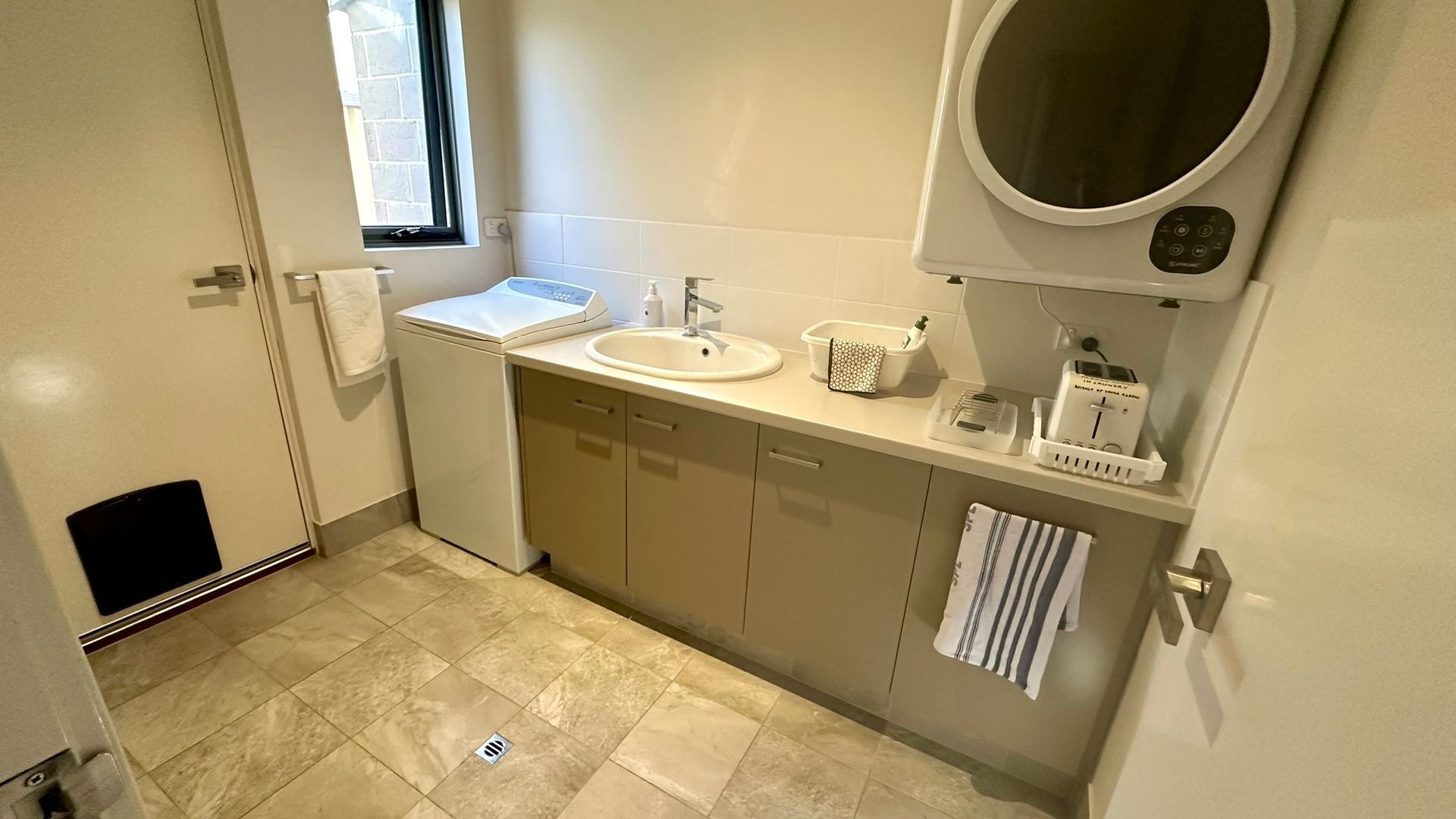 Een kleine badkamer met een wastafel, spiegel en raam.