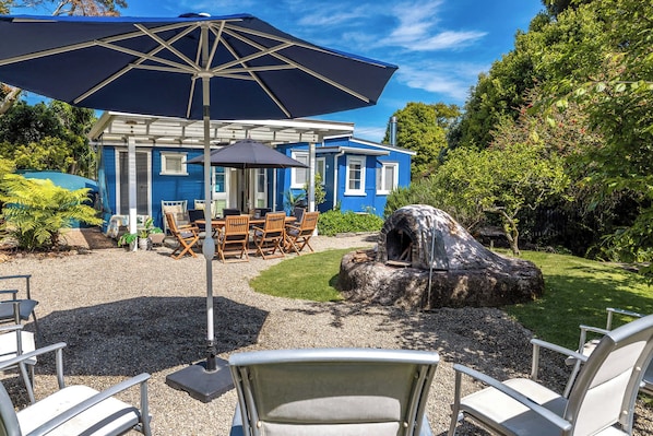 Et blåt hus med en patio, udendørs møbler og en stenovn.