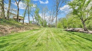 A residential property with a well-maintained lawn, a large tree, and a house with a balcony.