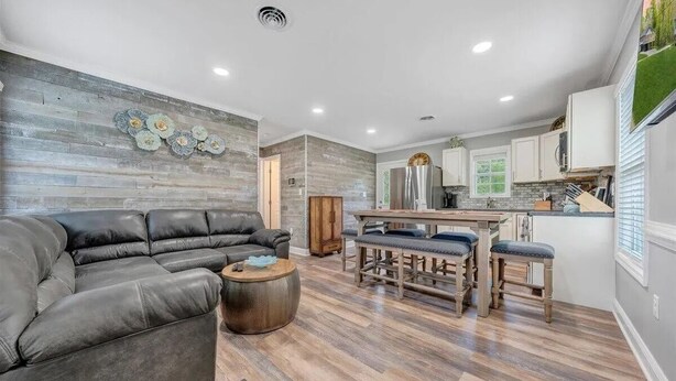 A modern kitchen with white cabinets, a central island, and a dining area with stools.