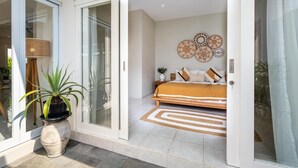 A modern bedroom with a bed, a large potted plant, and decorative wall art.