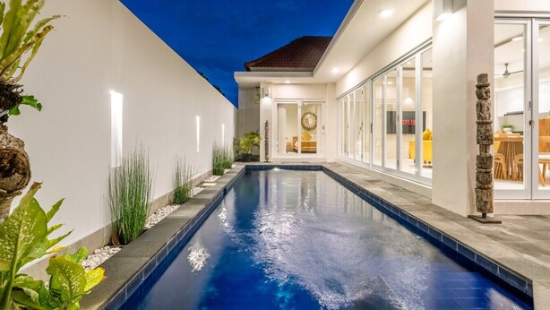 A modern house with a swimming pool, a dining area, and a visible kitchen.