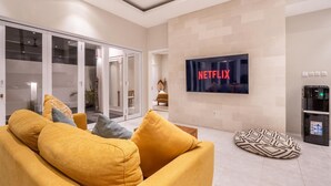 A modern living room with a yellow sofa, a Netflix TV, and a water dispenser.