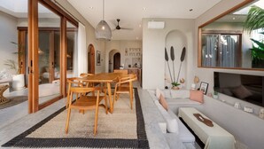 A modern interior with a dining area, sofa, and large windows. - Villa Glentana - 3BR EPIC Sunset Villa (Seseh)