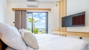 A hotel room with a bed, a TV mounted on the wall, and a window with curtains.