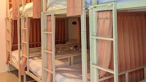 Dormitorio con literas, cortinas, una escalera y una puerta pequeña.