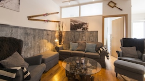 Una sala de estar moderna con un sofá gris, una mesa de centro de vidrio y una pared de acento de madera.