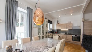Una cocina moderna con armarios de madera, una zona de comedor con mantel a rayas y una lámpara colgante.