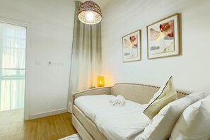 A bedroom with a bed, a bedside lamp, a window, and two framed pictures on the wall.