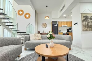 A modern living room with a grey sofa, a coffee table, and a vase of flowers.