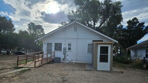 Une petite maison de plain-pied avec une terrasse en bois et un petit porche.