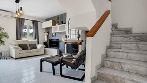 A modern living room with a sofa, coffee table, TV, fireplace, and a staircase. - Capitulaciones - Swimming pool, garage, 3 bedrooms, terrace (Torremolinos)