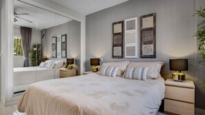 A bedroom with a large bed, bedside tables, a mirror, and wall art. - Capitulaciones - Swimming pool, garage, 3 bedrooms, terrace (Torremolinos)