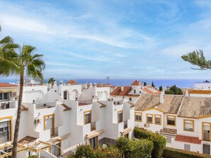 A coastal residential area with white buildings, red-tiled roofs, and a clear view of the sea.