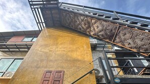A multi-story building with a yellow facade, a wooden door, and a metal staircase. - Golden Mango House (Sam Roi Yot)