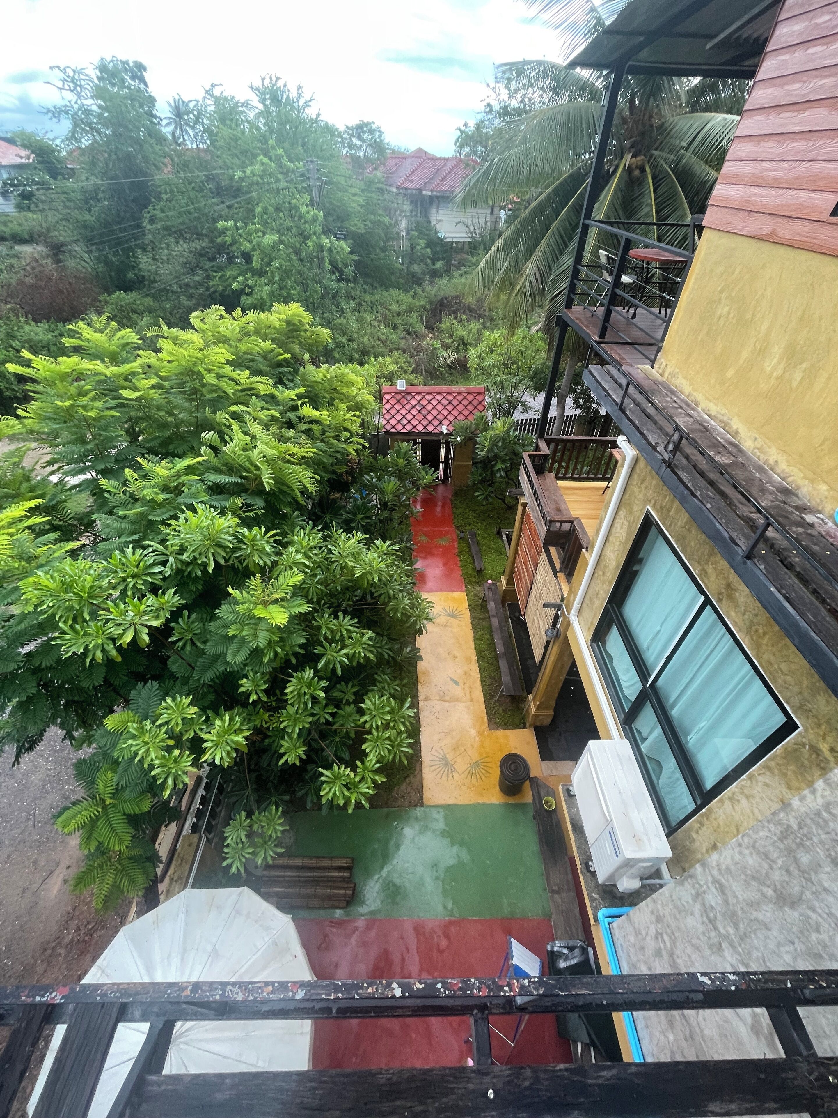 A multi-level building with a red-roofed structure in the center, surrounded by lush greenery.