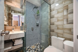 Une salle de bain moderne avec une douche à parois de verre, un lavabo en marbre et des toilettes.