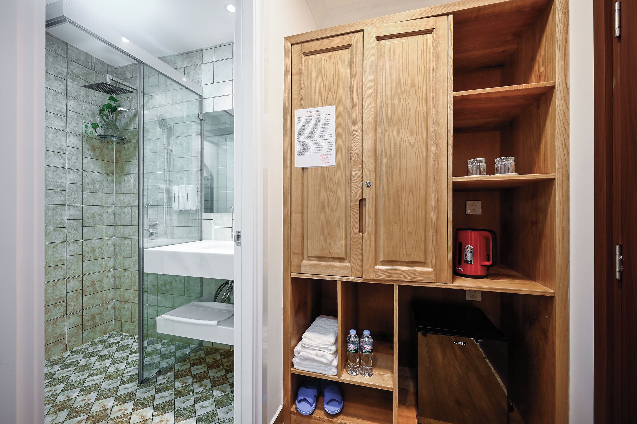 Une salle de bain avec une douche en verre, un lavabo et un meuble en bois doté d’étagères.