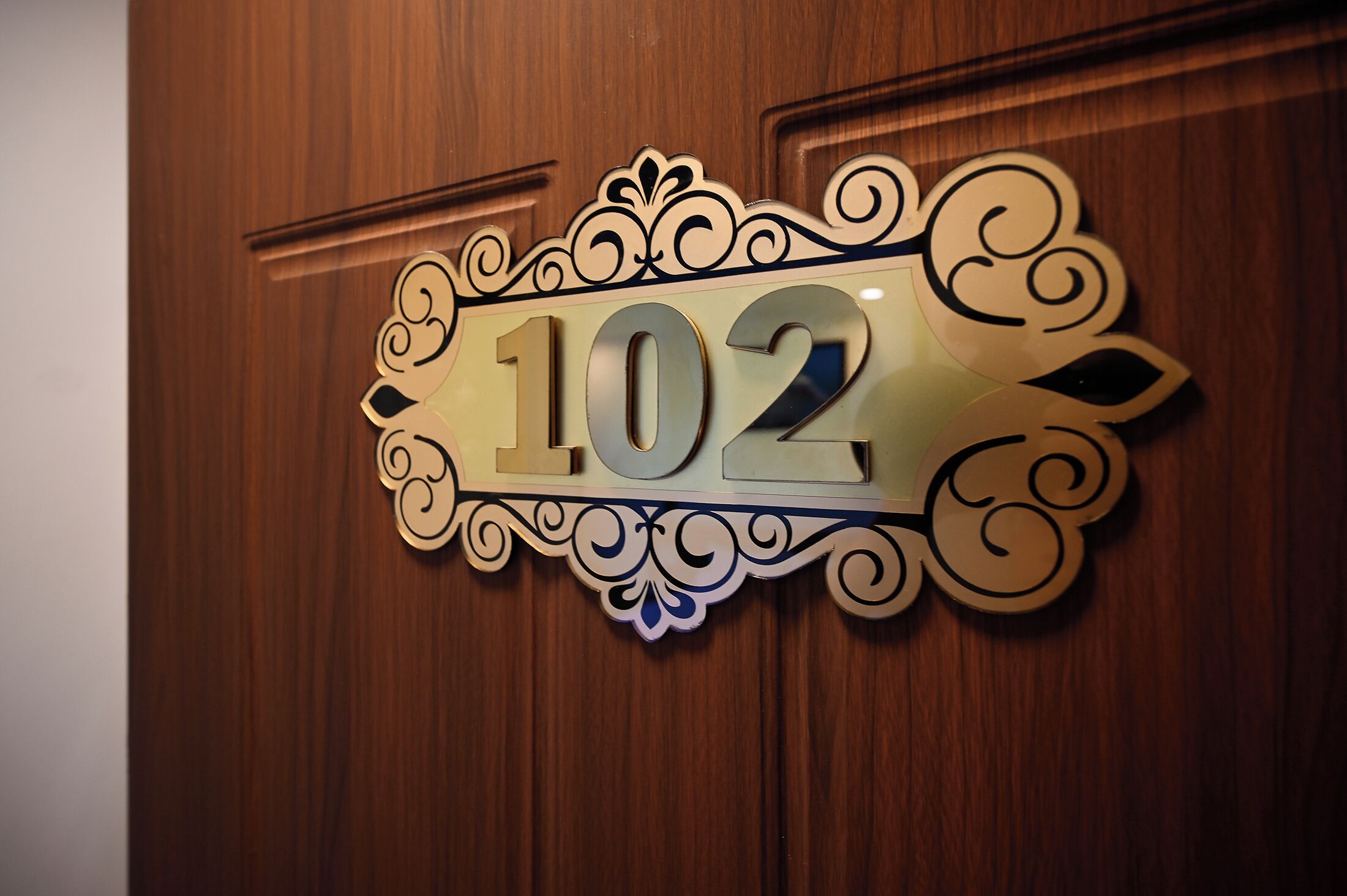 Una puerta de madera con un letrero decorativo que indica el número de habitación 102.