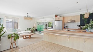 A modern kitchen with a central island, white cabinetry, and a hanging basket. - Waterfront Canal Escape in Burleigh (Burleigh Waters)