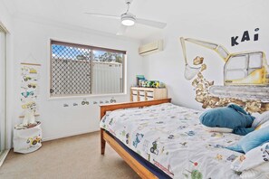 A bedroom with a bed, a ceiling fan, a window, and a wall with a construction-themed mural. - Waterfront Canal Escape in Burleigh (Burleigh Waters)