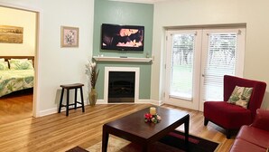 Una sala de estar con chimenea, televisor y un sillón rojo.