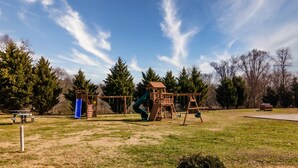 Un parque infantil con tobogán, columpios y una estructura para escalar.
