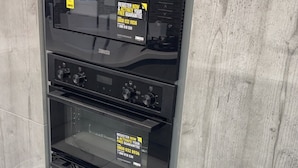 A commercial oven with a digital control panel and a glass door, installed in a kitchen with a grey marble backsplash.