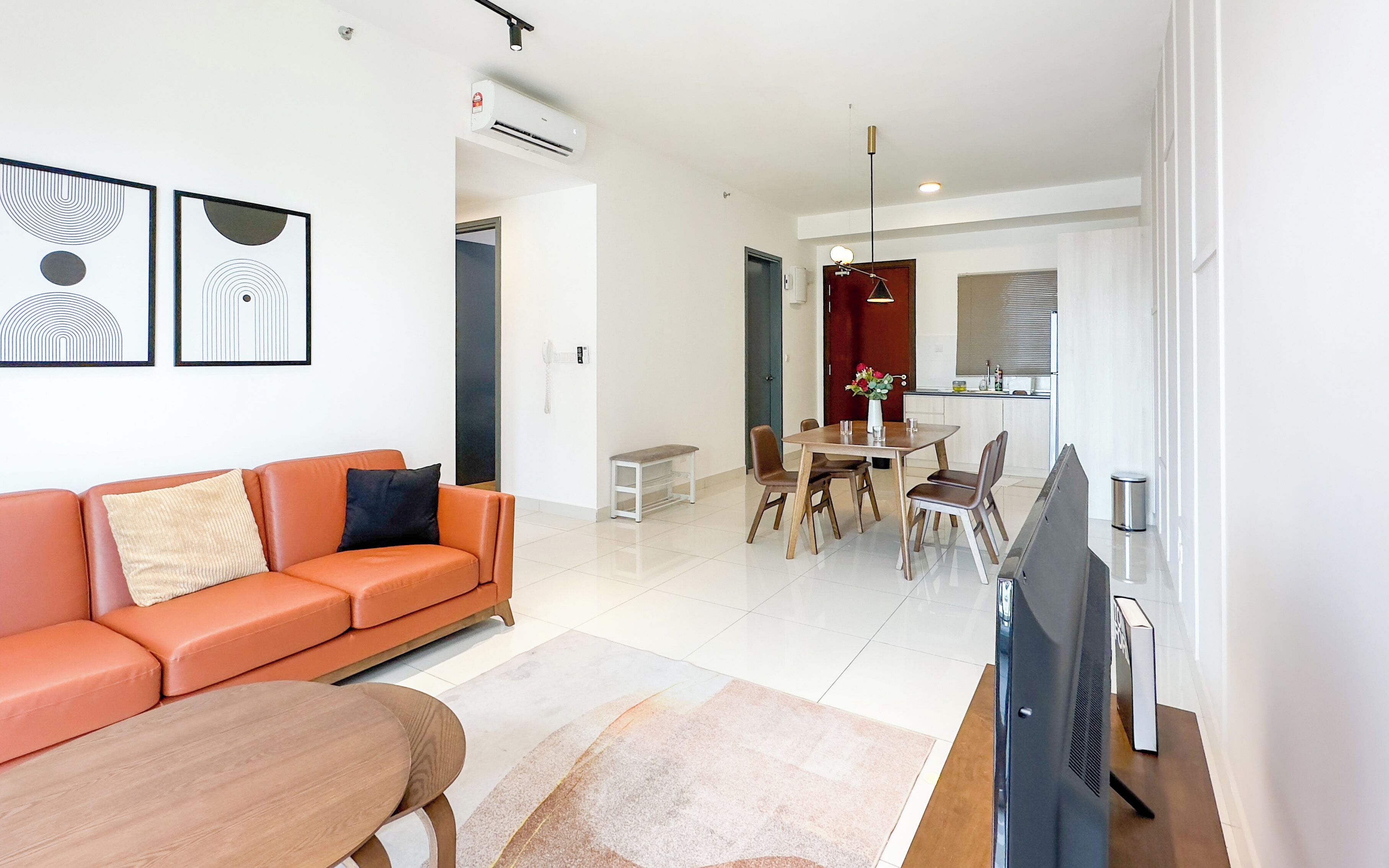Un salon moderne avec un canapé, une table à manger et un téléviseur à écran plat.