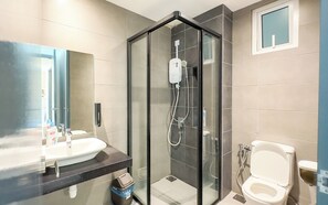 Un baño moderno con ducha envuelta en vidrio, un lavamanos y un inodoro.