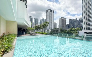 Piscina en la azotea con vistas a un paisaje urbano, rodeada de vegetación y arquitectura moderna.