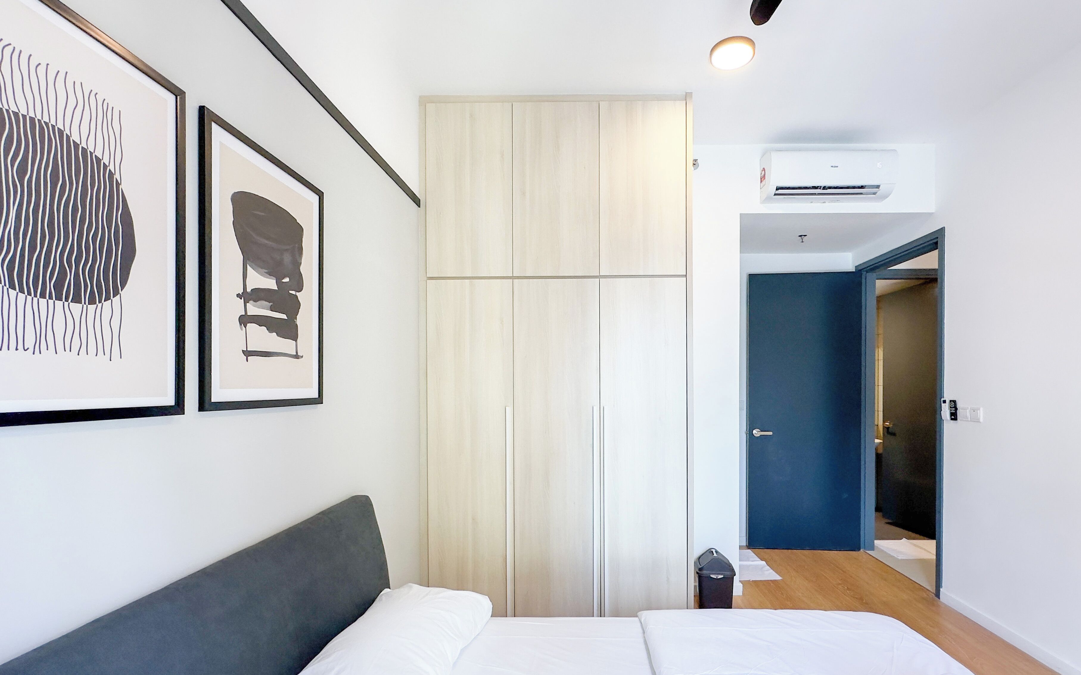 A bedroom with a bed, a wardrobe, and an air conditioning unit.