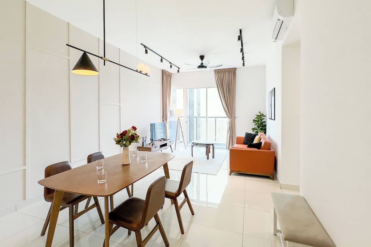 A modern dining area with a wooden table and chairs, a vase of flowers, and a television.
