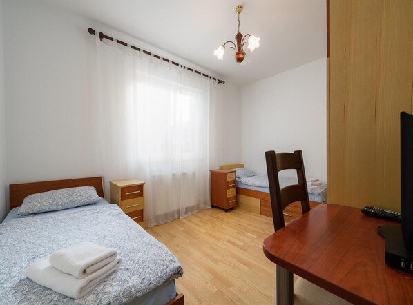 Un dormitorio con cama, escritorio, silla, armario de madera y candelabro.