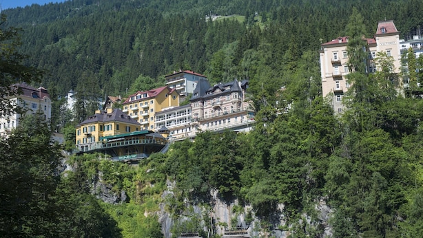 Un hotel de varios pisos, con balcones y montañas al fondo.