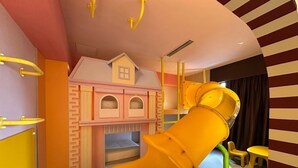 Ein Kinderspielbereich mit Rutsche, Spielgeräten und einem kleinen Haus.