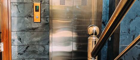 A modern elevator with a digital display, emergency switch, and a red emergency alarm.
