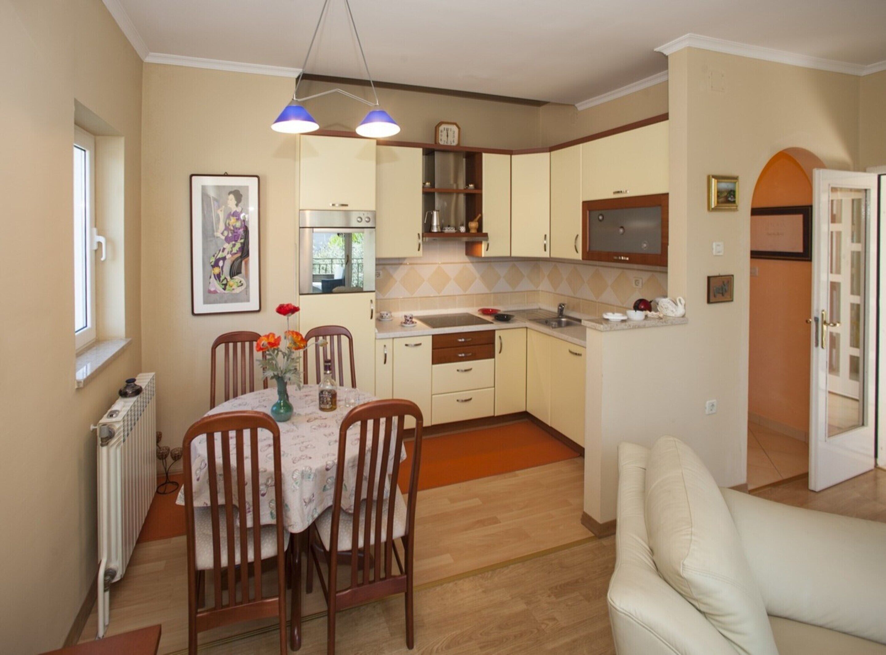 A compact kitchen with a dining area, a radiator, and a sofa.
