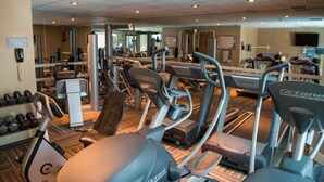 Un gimnasio con cintas de correr, bicicletas estáticas y máquinas de pesas.