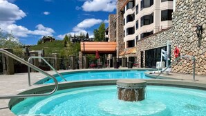 Una piscina con un muro de piedra y un edificio al fondo.
