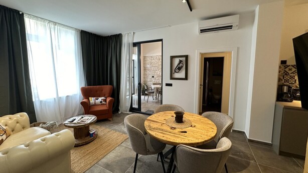 A modern living room with a leather sofa, a wooden coffee table, and a dining area with a round table and chairs. - Apartment Urban Living (Porec)