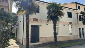 A two-story building with a beige facade, a black door, and a small balcony. - Apartment Urban Living (Porec)