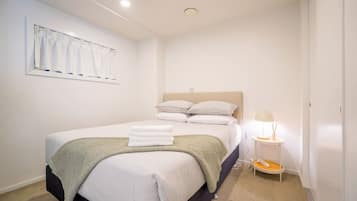 A bedroom with a bed, pillows, a bedside lamp, and a window with curtains.